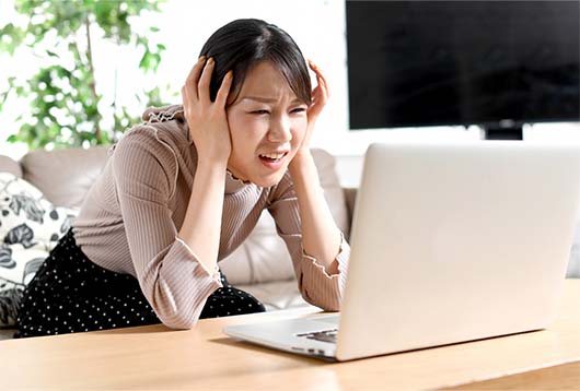 パソコンの前で悩む女性